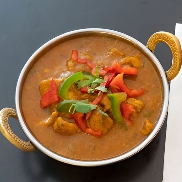 Dhaba Indian Cuisine's chicken curry with bell peppers and cilantro in a metal serving bowl.