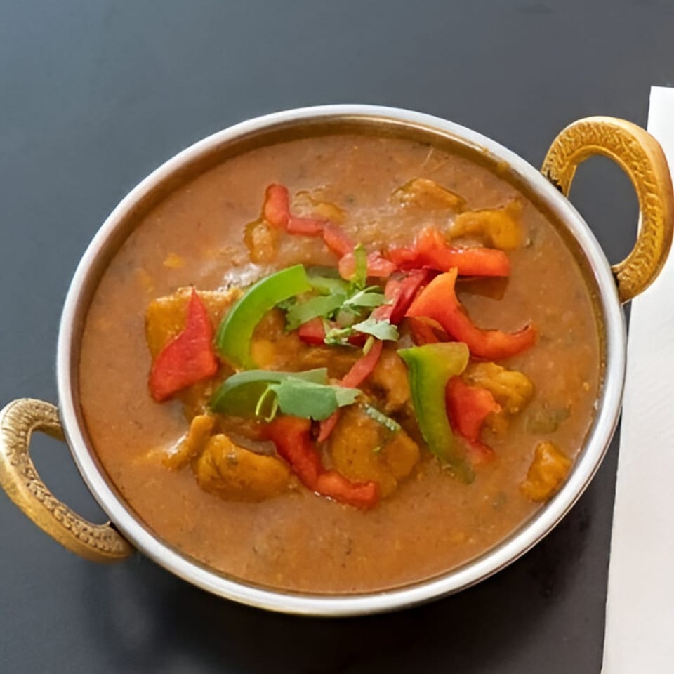 Dhaba Indian Cuisine's chicken curry with bell peppers and cilantro in a metal serving bowl.