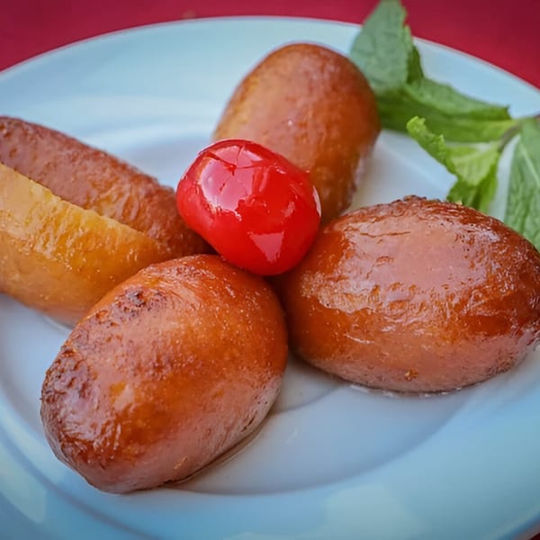 Gulab Jamun, a traditional Indian dessert, garnished with a red cherry and mint leaves.
