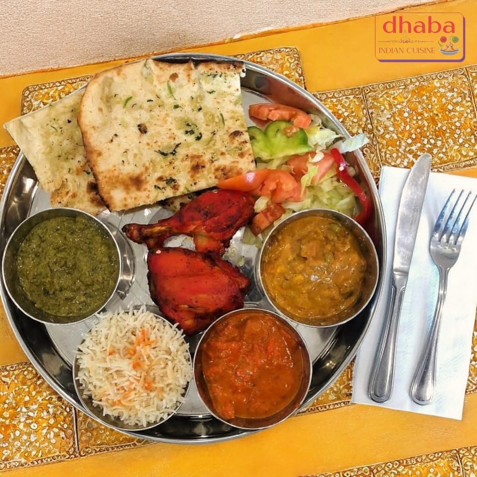 A Dhaba Indian Cuisine thali with tandoori chicken, naan, rice, salad, and three curries.